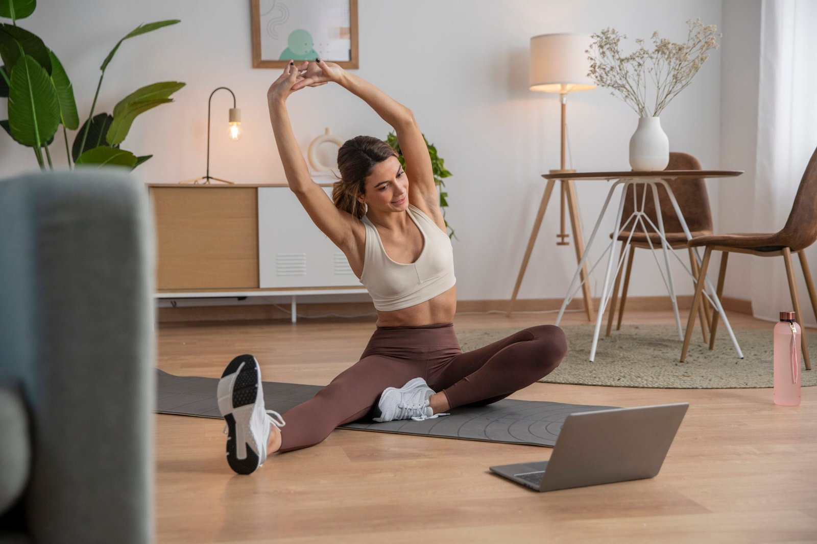 mujer milenial con piel hidratada haciendo practicas de yoga como parte de su rutina de cuidado personal en su departamento con decorado contemporáneo.