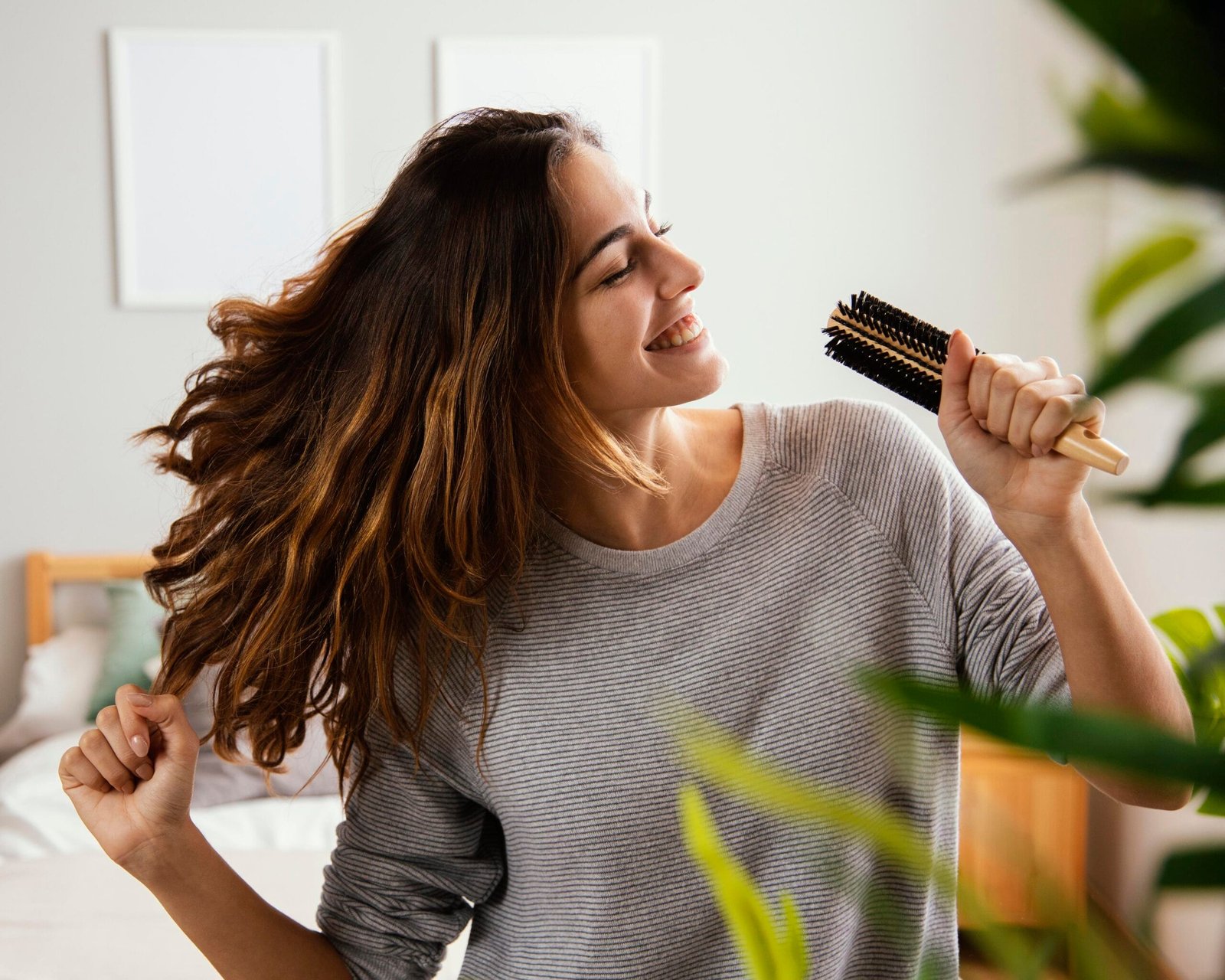 chica de piel morena en su cuarto sosteniendo su cepillo de cabello como un micrófono mientras canta muy feliz