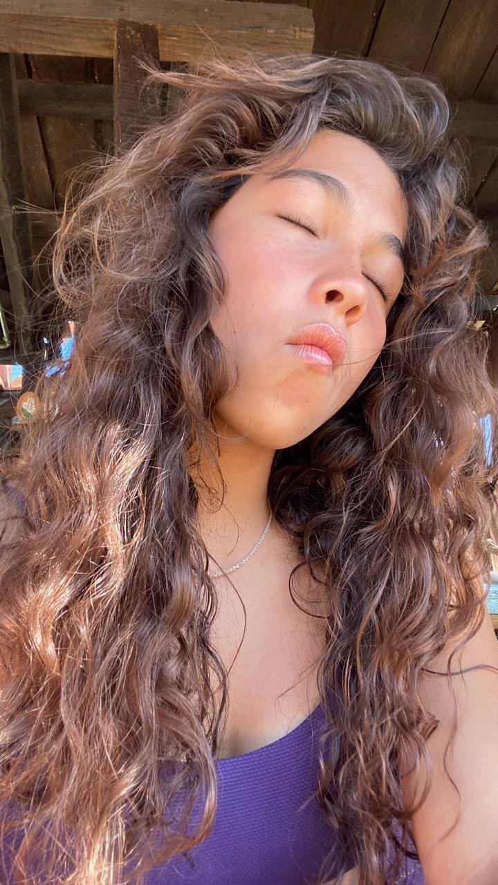 chica ondulada 2 b, recién salida del mar, castaña con toques dorados, cerrando los ojos, posando con la boca con un poco de maquillaje y en traje de baño