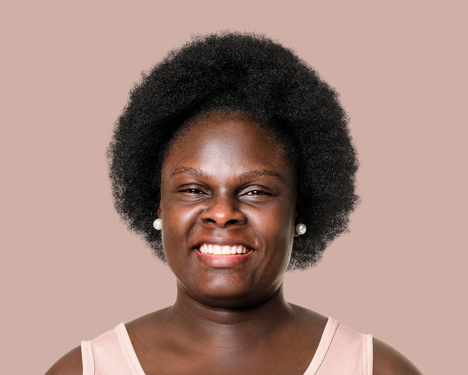 mujer negra afro, sonriendo, con cabello muy corto y afro 4c, con aretes, dientes blancos, marcas evidentes de la sonrisa, teniendo demasiado volumen, cabello negro y rizos muy cerrados